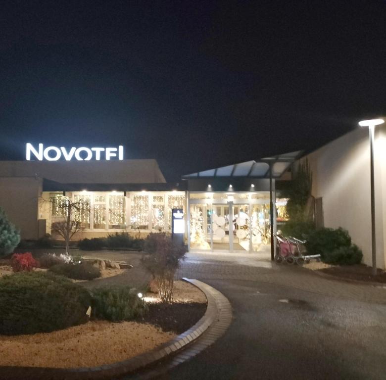 un magasin de nouitkat la nuit avec un panneau sur celui-ci dans l'établissement Novotel Dijon Sud, à Dijon