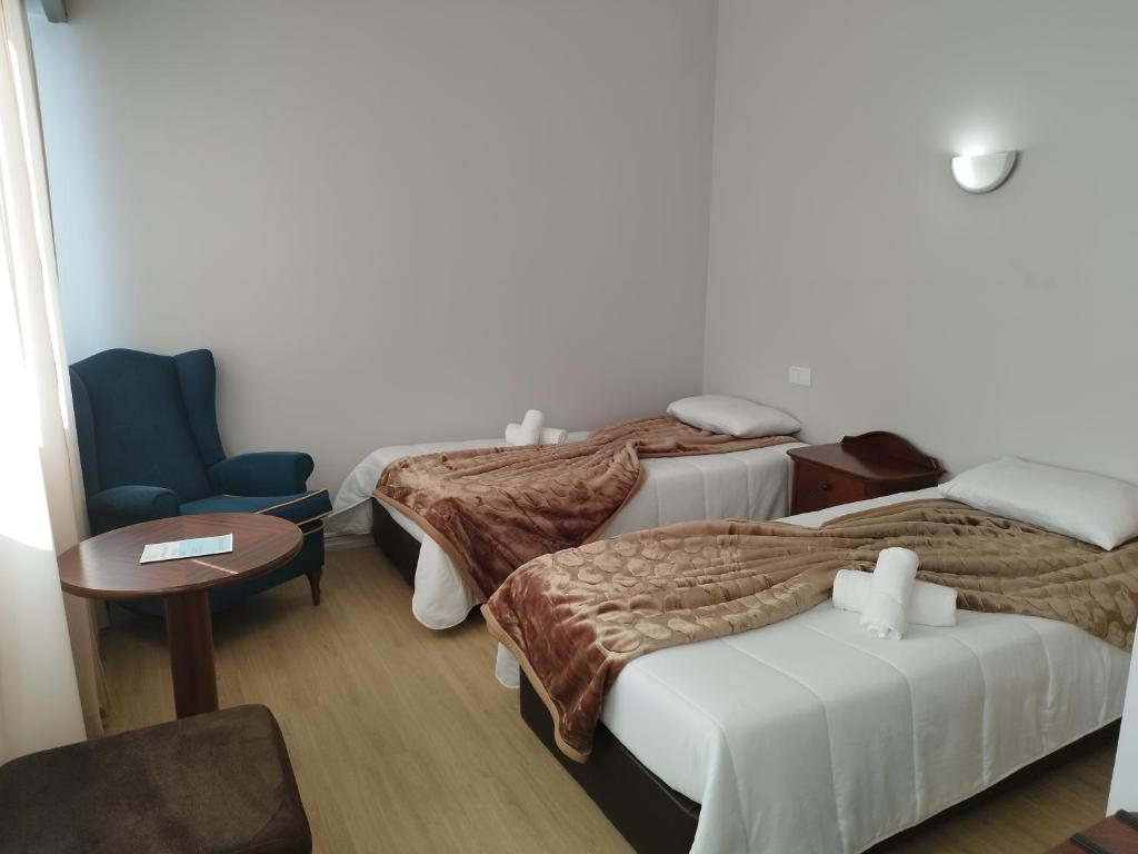 pokój hotelowy z 3 łóżkami i krzesłem w obiekcie Alojamento Central II w Funchal