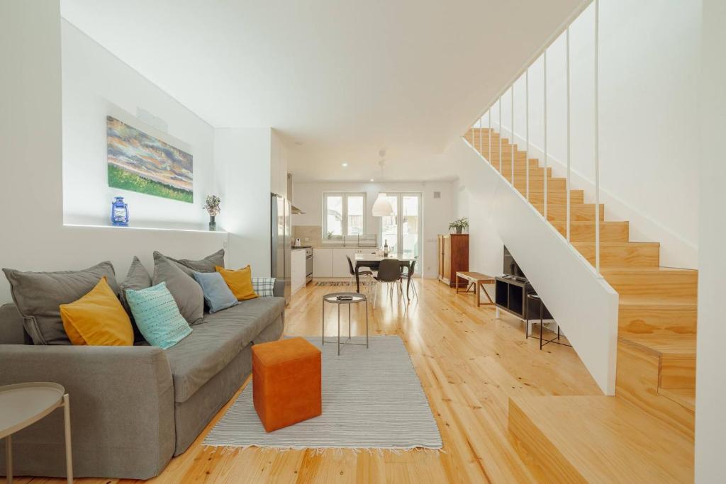 uma sala de estar com um sofá cinzento e uma escada em Modern Villa by Hosty no Porto