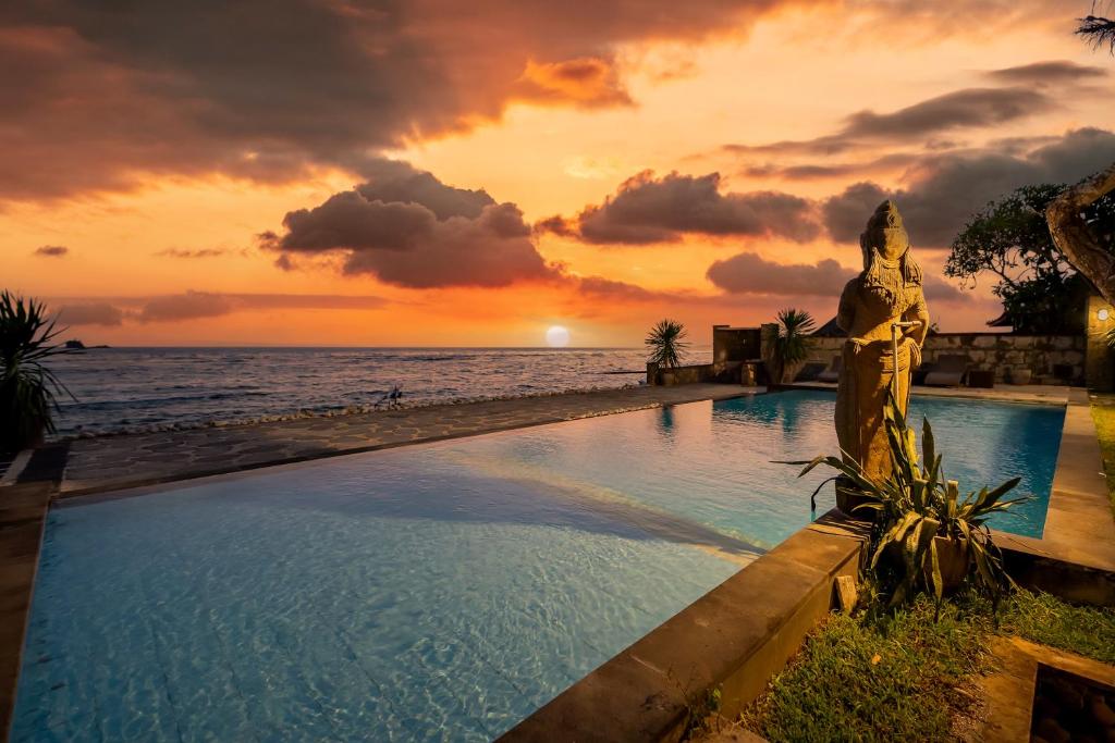 basen na plaży z zachodem słońca w tle w obiekcie Ganesh Beach Hotel w mieście Candidasa