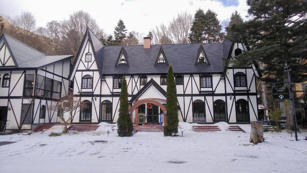 uma grande casa a preto e branco na neve em ペンションアルマ em Katashina