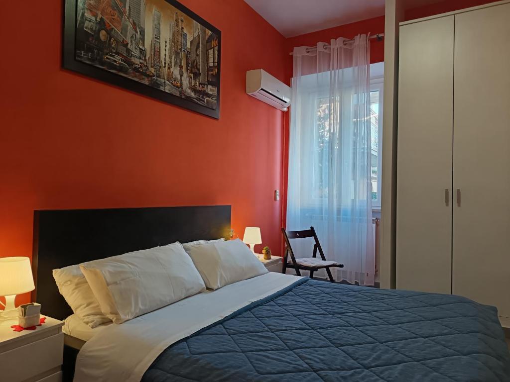 a bedroom with red walls and a bed and a chair at Adriatic Room 50 m dalla stazione Ferroviaria di Ciampino e dalla navetta aeroportuale in Ciampino