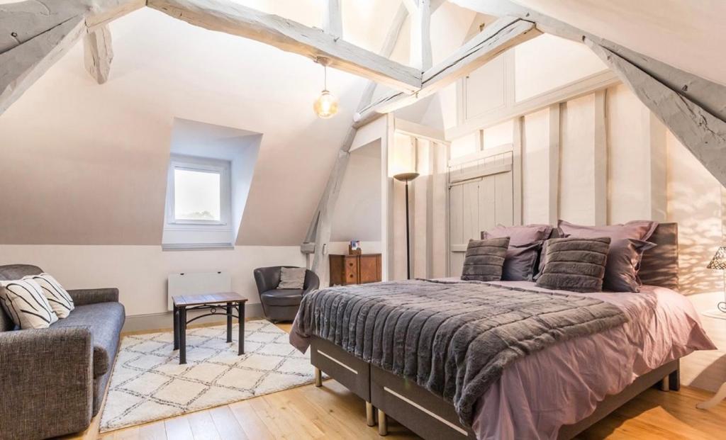 een slaapkamer met een groot bed en een stoel bij Villa du Vieux Château in Les Andelys