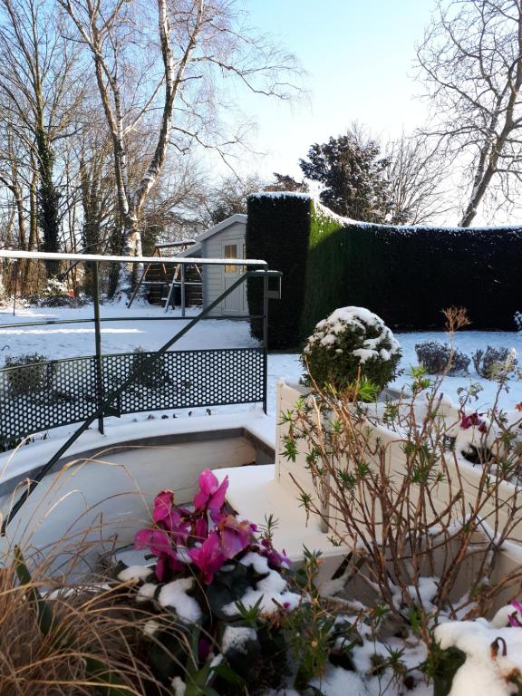 um jardim coberto de neve com flores e uma escada em Studio La Rotonde em Waterloo