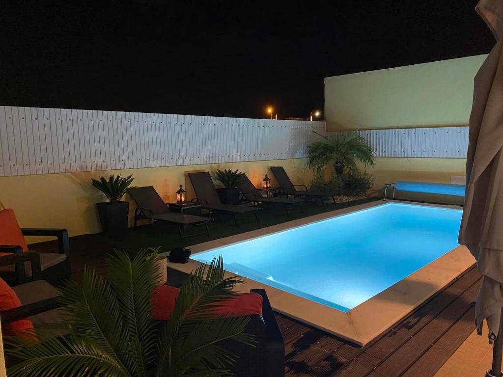 - une grande piscine de nuit avec des chaises et des tables dans l'établissement Zion guest house, à Almada