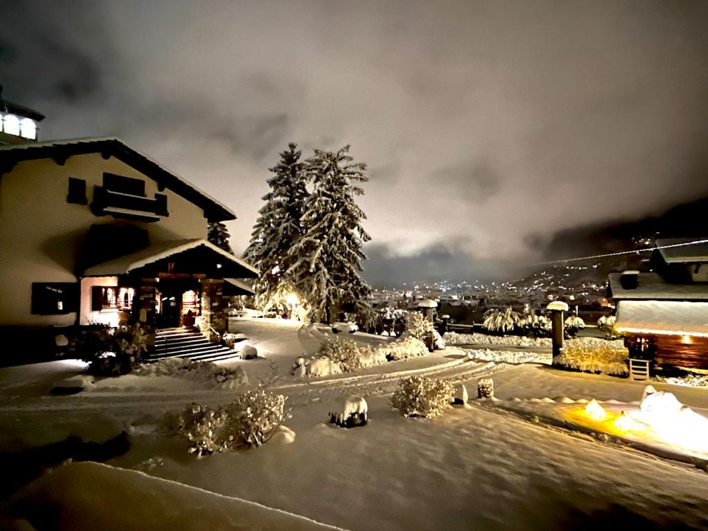 un patio cubierto de nieve con una casa en el fondo en Hotel Milleluci, en Aosta