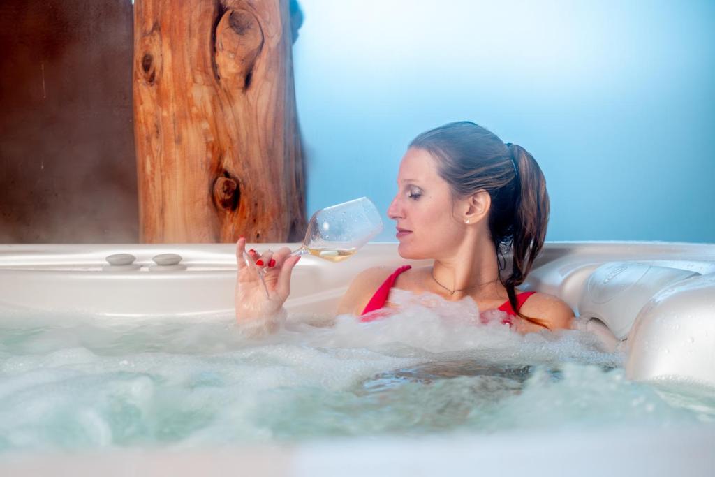 een vrouw in een bad met een glas wijn bij CASA da CARMEN - Relax & Tradizione in Mezzolombardo