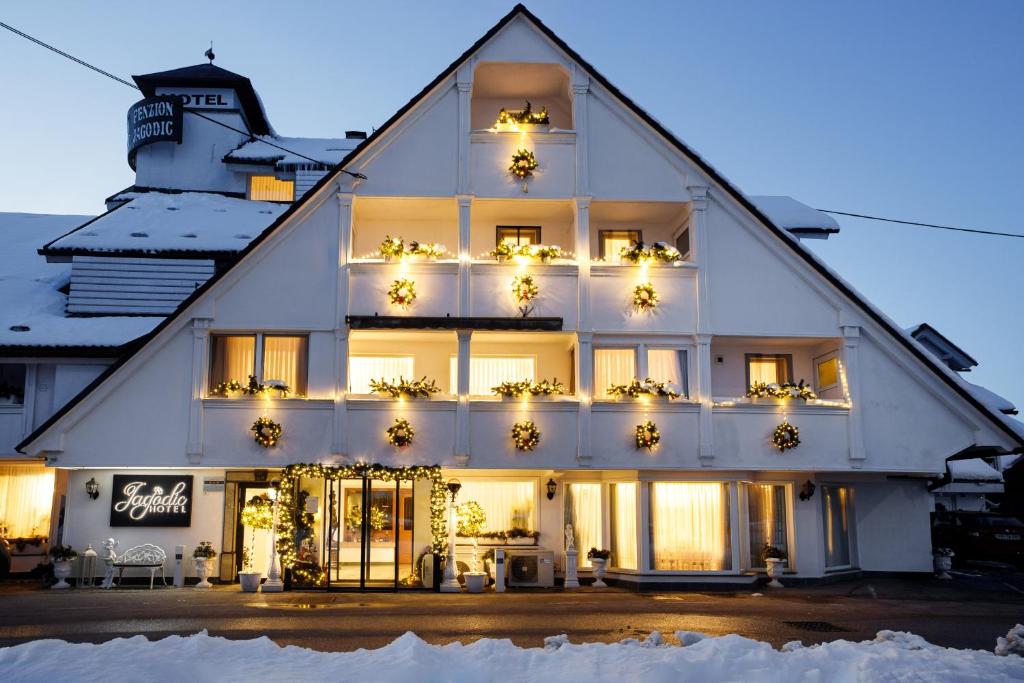 um grande edifício branco com luzes de Natal em Jagodic Garni Hotel em Cerklje na Gorenjskem