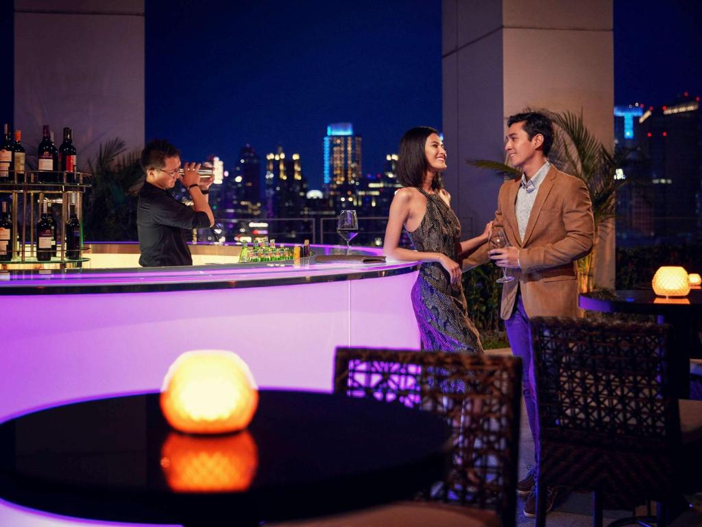 Ein Mann und eine Frau stehen an einer Bar in der Unterkunft Fairmont Jakarta in Jakarta