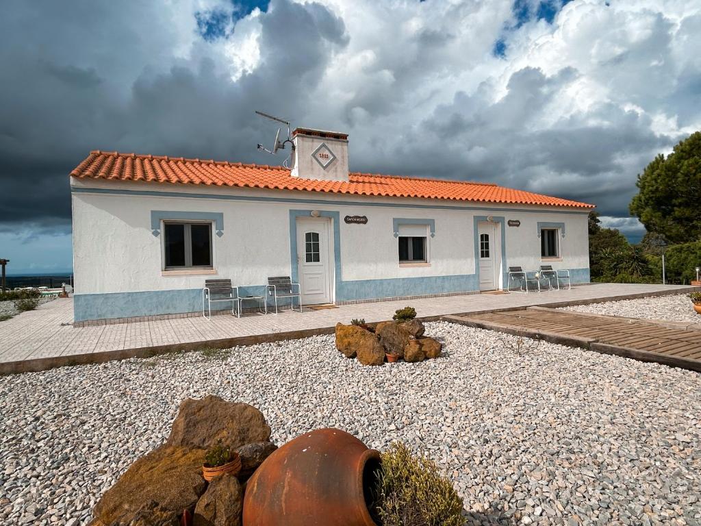 uma pequena casa branca com um relógio no telhado em Monte Sardinha em Santiago do Cacém