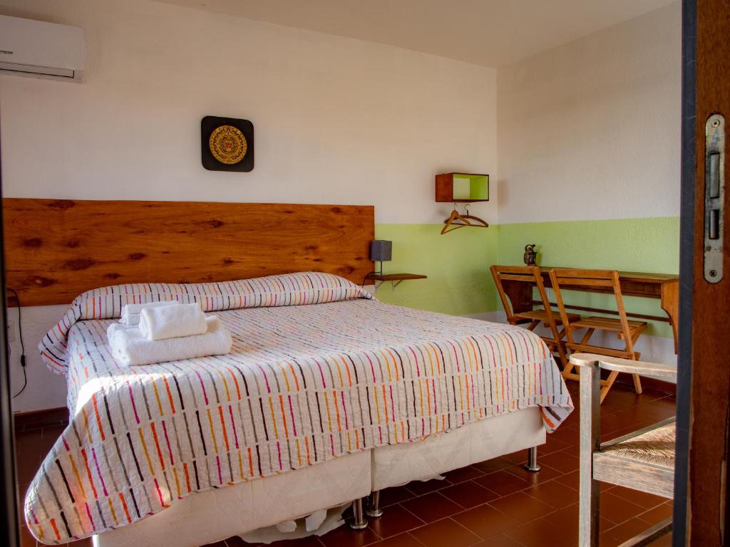 ein Schlafzimmer mit einem Bett, einem Tisch und einer Uhr in der Unterkunft cuatro lunas hotel in Punta Del Diablo