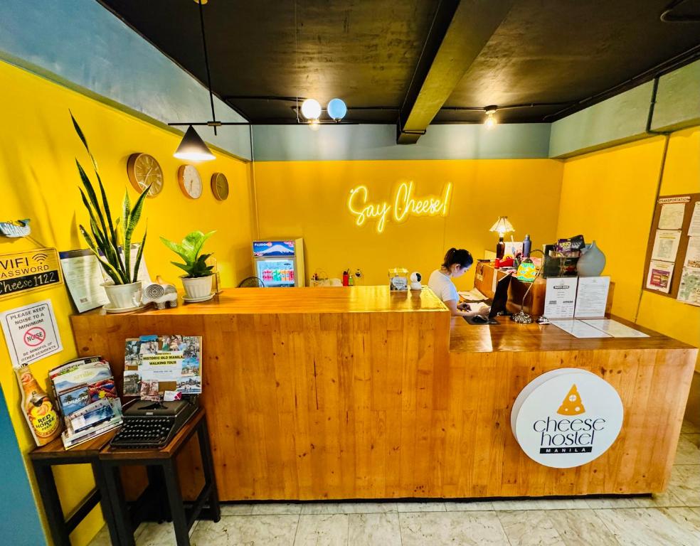 Cheese Hostel Manila في مانيلا: وجود امرأة جالسة في كونتر مطعم