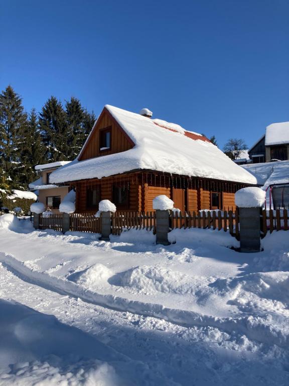 une cabane en rondins recouverte de neige avec une clôture dans l'établissement Drevenica Silvia, à Liptovský Mikuláš