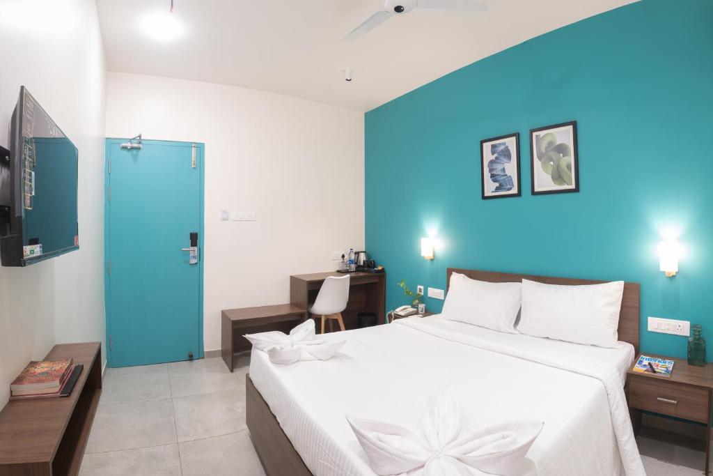 Un dormitorio con una gran cama blanca y una pared azul en The Elements Inn, en Madurai