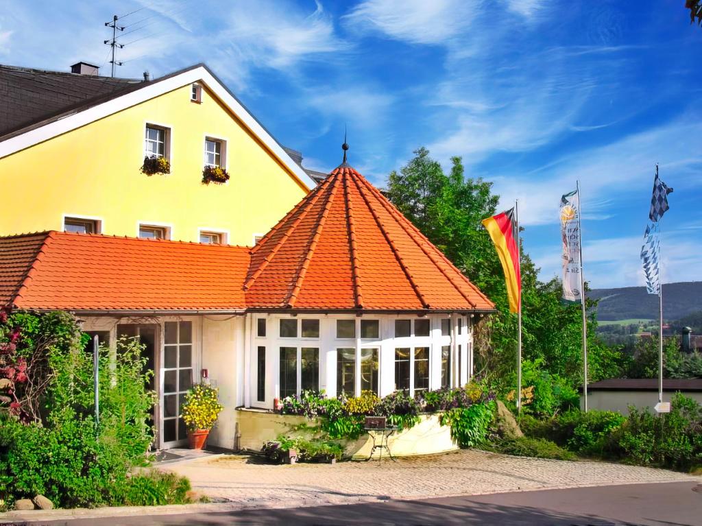 ein gelbes Haus mit orangefarbenem Dach in der Unterkunft WAGNERS Hotel Schönblick, C&C Hotels und Vertrieb GmbH in Fichtelberg