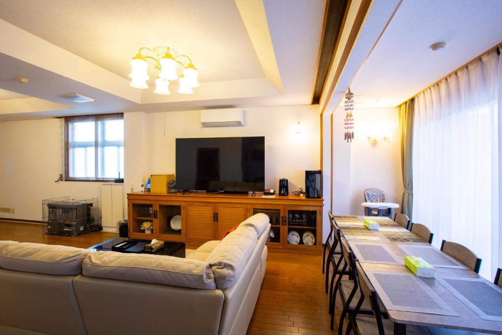 un soggiorno con divano e tavolo con sedie di Bigstone Terrace suite　堤町 ad Aomori