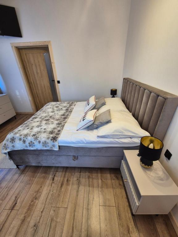 - un grand lit dans une chambre dotée de parquet dans l'établissement Apartament z jacuzzi U Parów, à Białka Tatrzańska