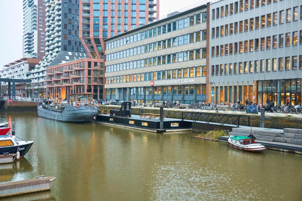 un río con barcos en una ciudad con edificios en De Coaster & Aquarium, en Róterdam