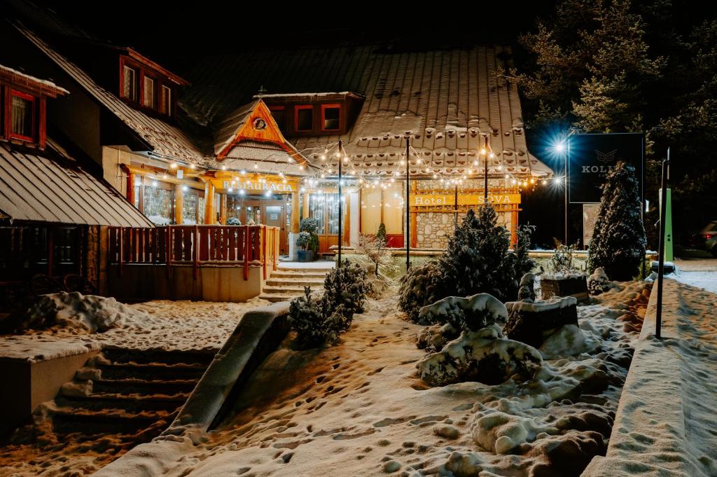 uma casa coberta de neve à noite com luzes em Penzión Sova Ždiar em Ždiar