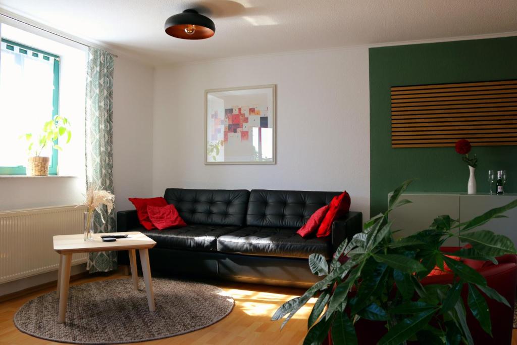 ein Wohnzimmer mit einem schwarzen Ledersofa und einem Tisch in der Unterkunft Ferienwohnung Villa Funcke in Eisenach