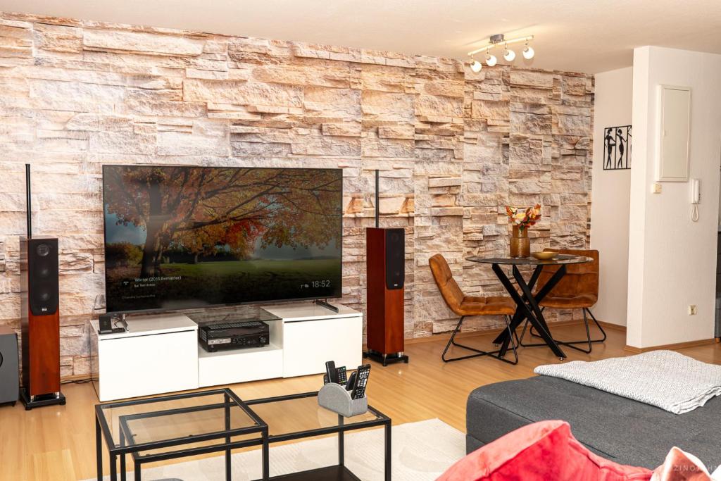 a living room with a large flat screen tv on a stone wall at Taros Home - Deluxe Apartment in Herrenberg