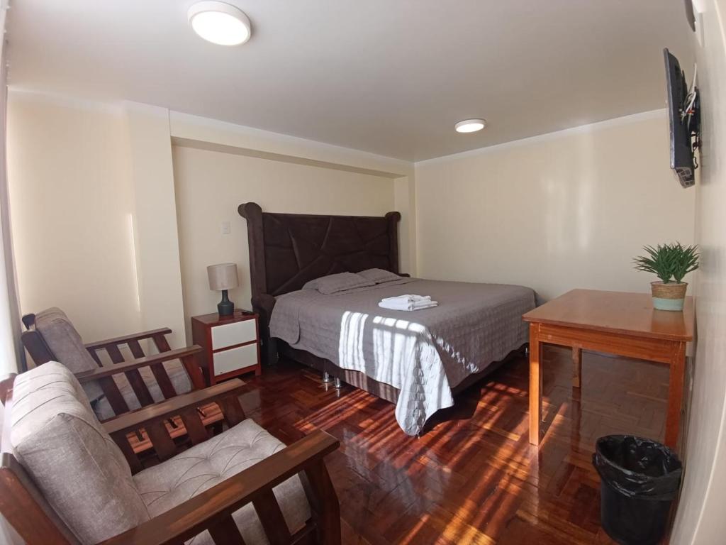 a bedroom with a bed and a table and a chair at casa SKALA in Puno