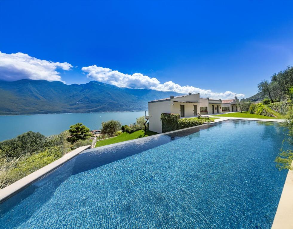 una piscina con vista su una casa e su un lago di LLAC Living Nature Hotel a Limone sul Garda