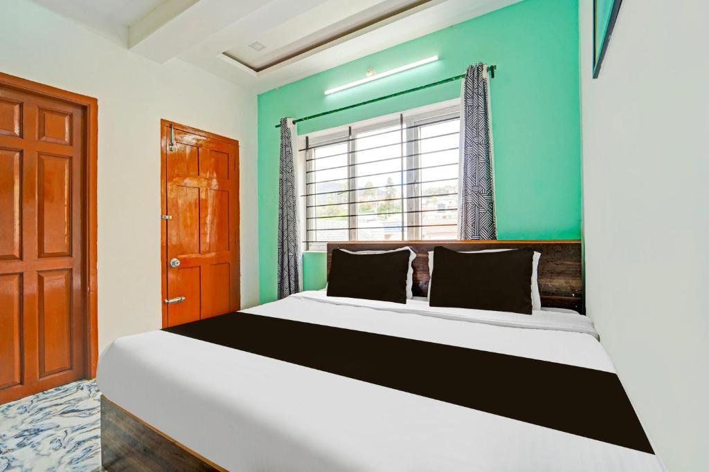 1 dormitorio con 1 cama grande y pared azul en Super Hotel O Vijaynagar Road formerly Anmol Peace Stay, en Ooty