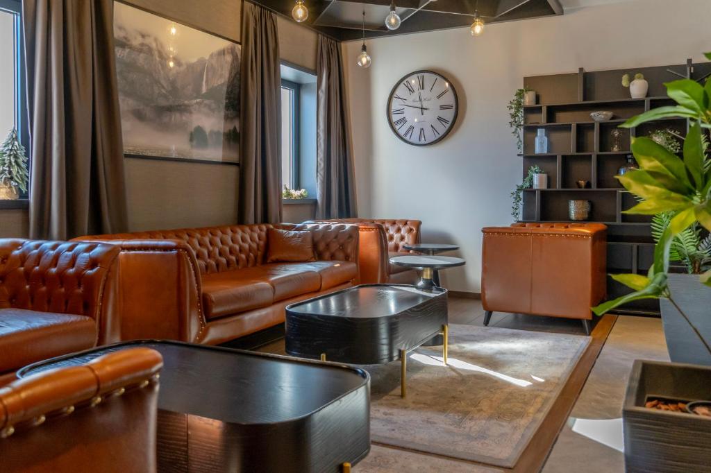 - un salon avec des canapés en cuir et une horloge dans l'établissement Hotel Rajska dolina Jahorina, à Jahorina