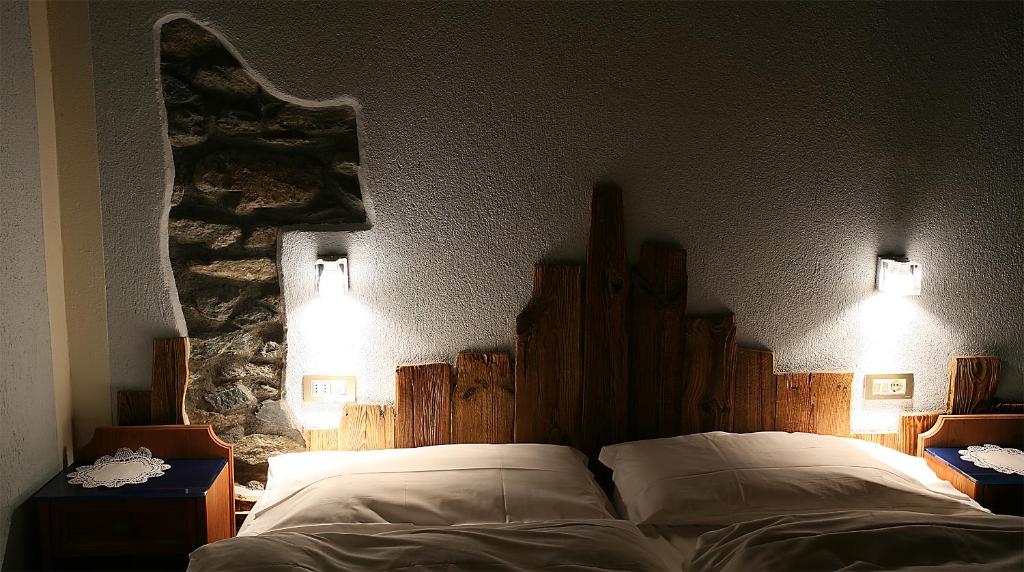 een slaapkamer met een bed en twee lampen aan de muur bij Hotel Meublé Gorret in Breuil-Cervinia