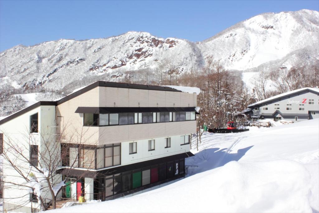 ein Gebäude im Schnee vor einem Berg in der Unterkunft Snow Freak Sunrise in Zao Onsen