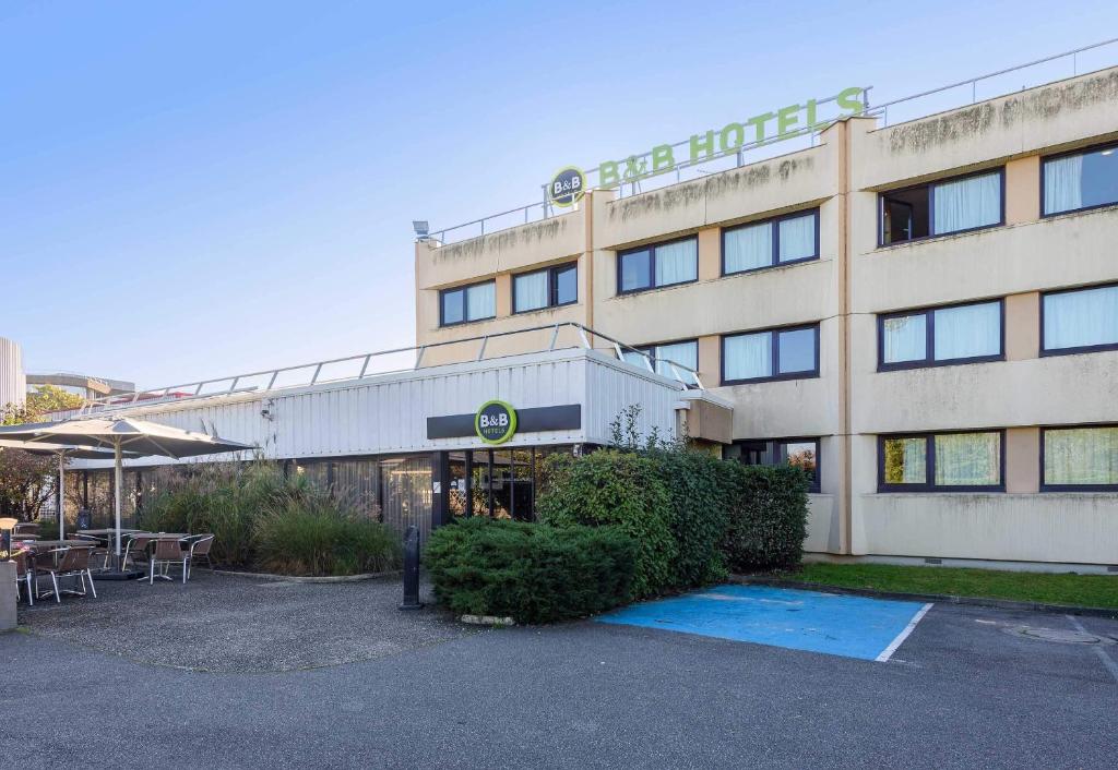 een gebouw met een tafel en stoelen ervoor bij B&B HOTEL Toulouse Université in Toulouse