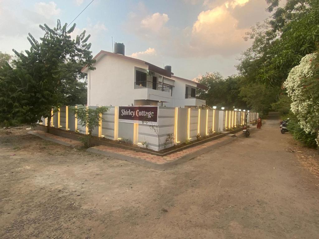 una casa blanca con un cartel en una valla en shirley cottage, en Daulatābād