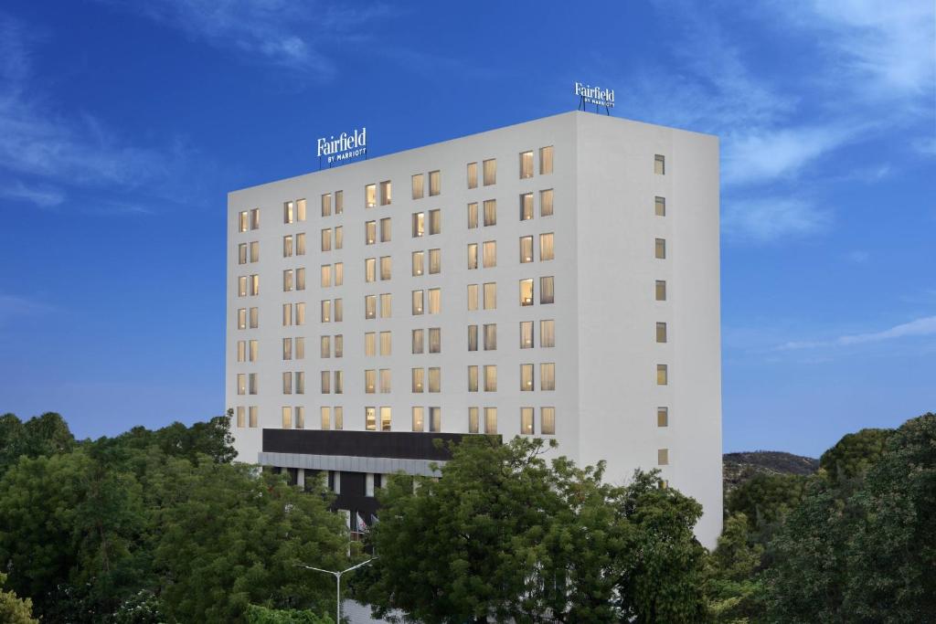 Fairfield by Marriott Ahmedabad في أحمد آباد: مبنى أبيض طويل وبه أشجار أمامه