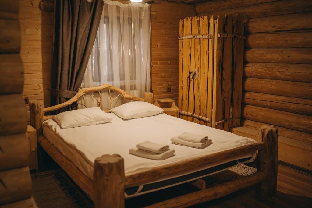 1 dormitorio con 1 cama en una cabaña de madera en Kisva Hotel, en Yablunytsya