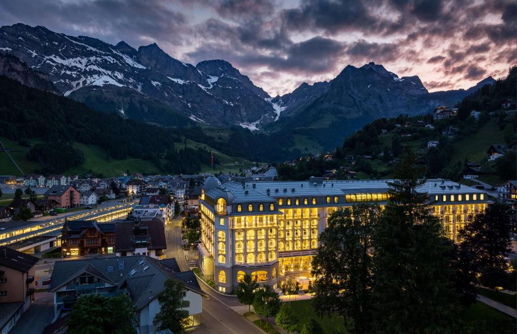 Kempinski Palace Engelberg في إنغيلبرغ: مبنى مضاء في الليل مع جبال في الخلفية