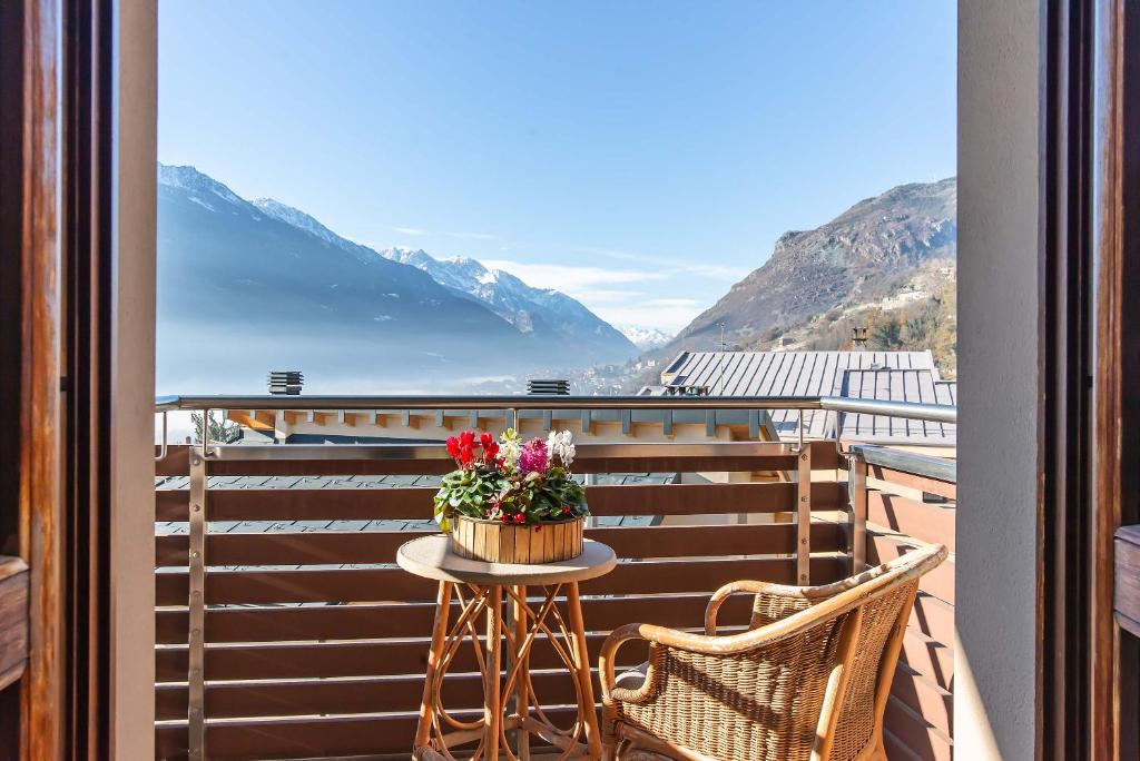 - une table avec des fleurs sur un balcon avec des montagnes dans l'établissement Relais Du Foyer, à Châtillon