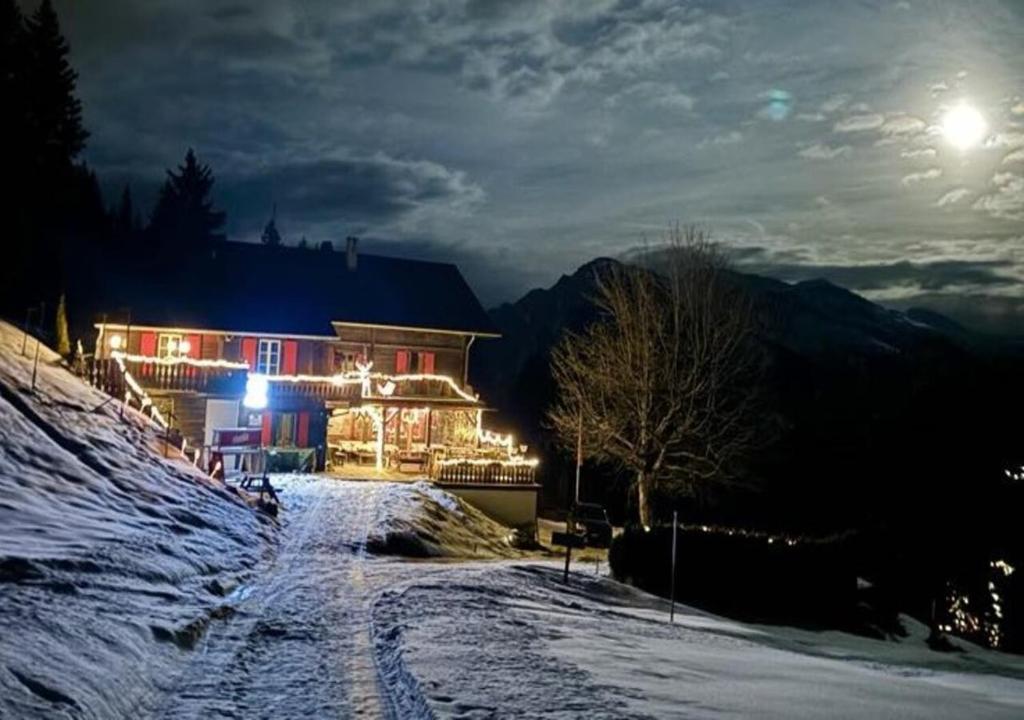 dom na pokrytym śniegiem wzgórzu w nocy w obiekcie Bergpension Battagliahütte w mieście Malix