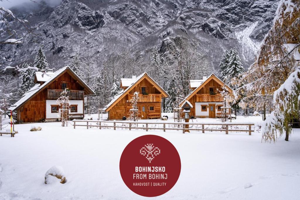 a cabin in the snow with mountains in the background at ALPIK Chalets - Bohinj in Bohinj