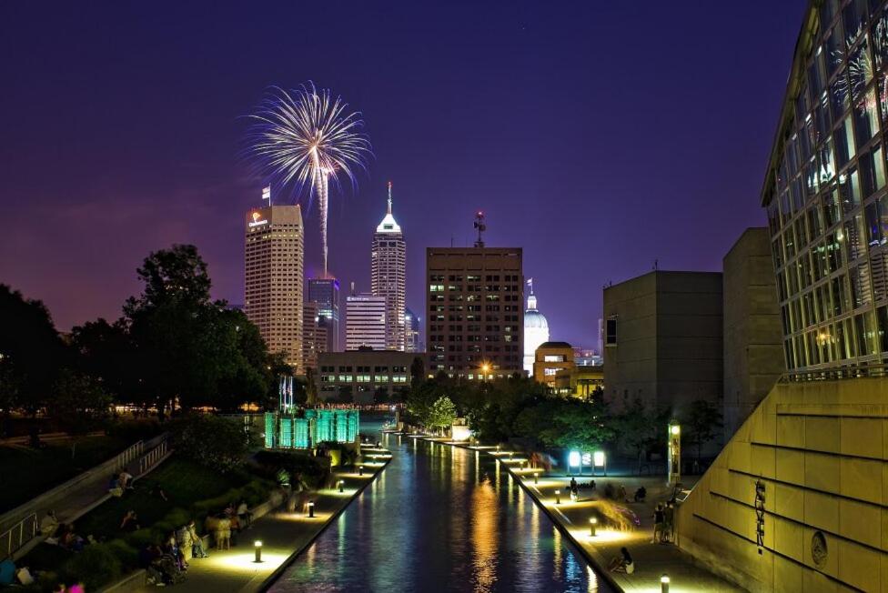 ein Fluss mit einer Stadt in der Nacht mit Feuerwerk in der Unterkunft FREE Parking & Lucas Oil- Conv Center Skywalk #3 in Indianapolis