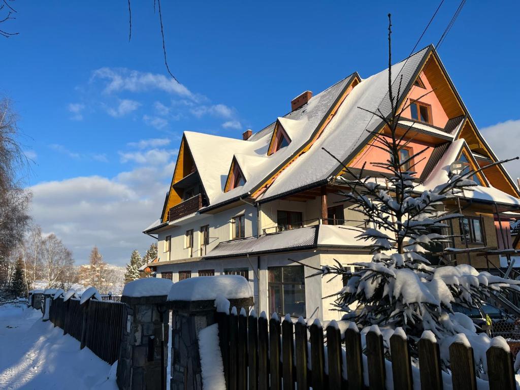 une maison recouverte de neige avec une clôture dans l'établissement Gościniec na Wierchu, à Bukowina Tatrzańska