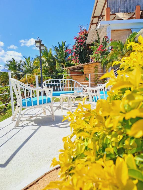 two chairs and a table on a porch with yellow flowers at Residence Ma Vie Là Ltee in Le Morne