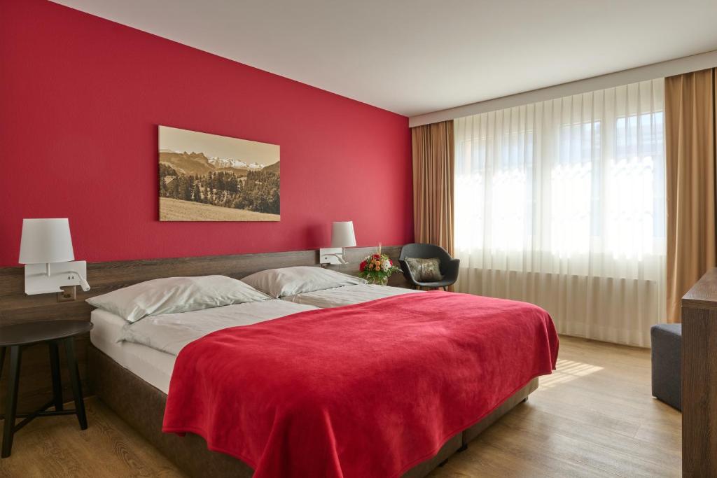 - une chambre rouge avec un grand lit et un mur rouge dans l'établissement Hotel Ochsen, à Menzingen