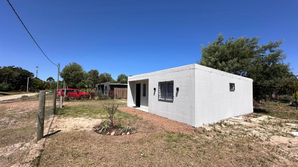 een wit gebouw in een veld met een rode truck bij Casitas Atlántida in Atlántida