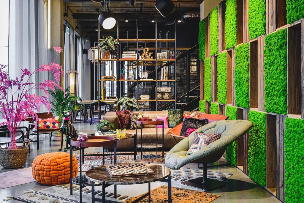 a room with a green wall with tables and chairs at Moxy Poznań Airport in Poznań