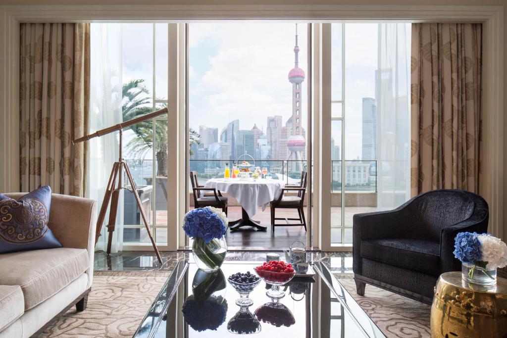 ein Wohnzimmer mit einem Tisch und Stadtblick in der Unterkunft The Peninsula Shanghai in Shanghai