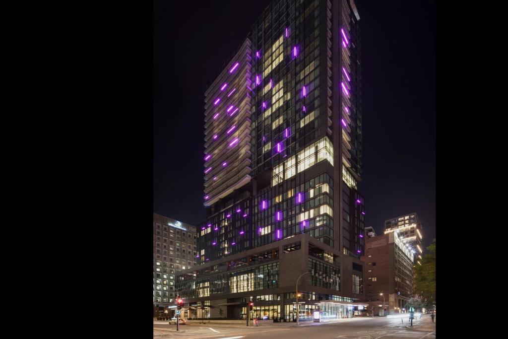 un edificio alto con luces moradas en él por la noche en HONEYROSE Hotel, Montreal, a Tribute Portfolio Hotel, en Montreal