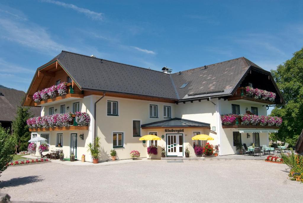 Une grande maison blanche avec des fleurs dans la cour dans l'établissement Gästehaus Kloibergütl, à Sankt Gilgen