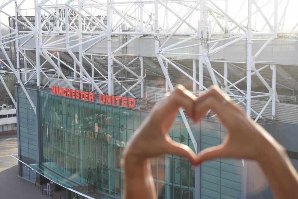 osoba robiąca znak serca przed budynkiem w obiekcie Hotel Football, Old Trafford, a Tribute Portfolio Hotel w Manchesterze