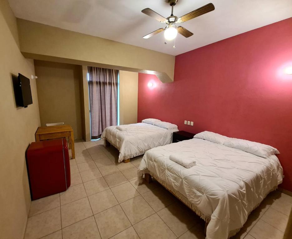 1 dormitorio con 2 camas y pared roja en Hotel Arcadia Cuernavaca, en Cuernavaca